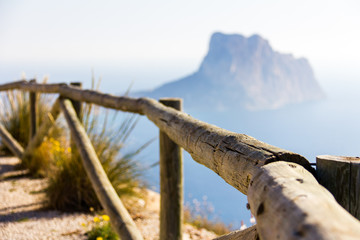 Wooden railing in a mountain path, the viewpoint of Morro de Toix, Penon of Ifach in Calpe is in the background