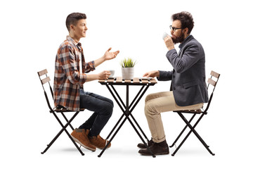 Young guy in a cafe talking to a bearded man drinking coffee