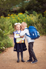 fair-haired cute happy children, brother and sister of the weather / twins 6 and 7 years old schoolchildren with knapsacks and books go to school ready for the beginning of the school year, portrait