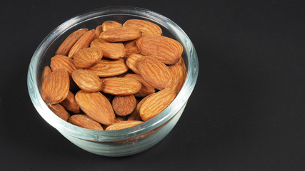 Raw almonds close up in bow and black background.