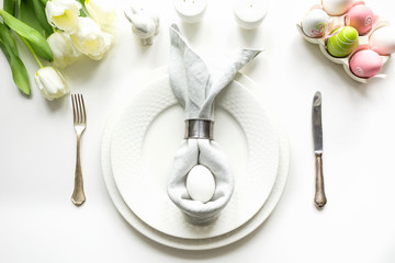 Easter dinner. Table setting with white tulip on white table. Top view.