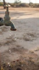 Dripping old brass water tap outdoors, water drops, exterior, day. Close, water droplets.