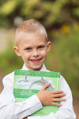 blond boy in a white shirt, schoolboy first-year student in the street reading a book about nature