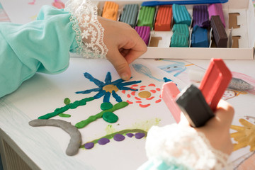 girl with plasticine at the table. Development of small motor skills of children. Child sculpts from plasticine