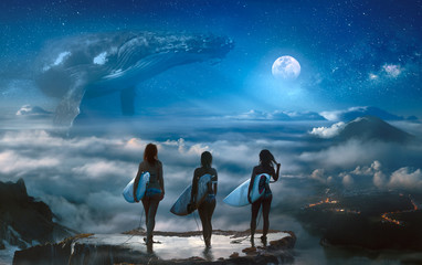 Surreal dream with three surfer girls standing on the top above clouds and landscape, big whale...