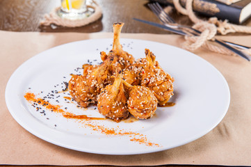 Roasted chicken wings in hot pepper and sesame oe the white plate. Selective focus, copy space.