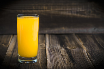 Glass of orange juice with fresh oranges on wood