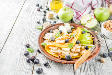Healthy breakfast food, Sweet stuffed egg omelette with fruits, berries and nuts, rustic wooden background copy space top view