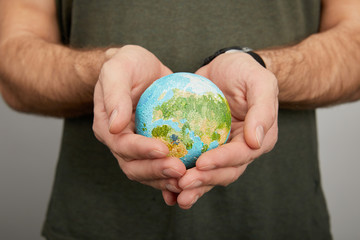 man holding planet model on grey background, earth day concept