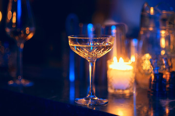 Vintage crystal glass on a blurred background. The atmosphere of a romantic dinner by candlelight.