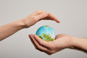 man and woman holding planet model on grey background, earth day concept