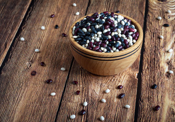 Colorful beans in a wooden bowl on a rustic table