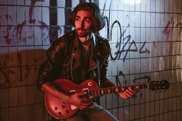 A street musician playing on guitar in the underpass. Vagrant lifestyle. Playing in the underpass...