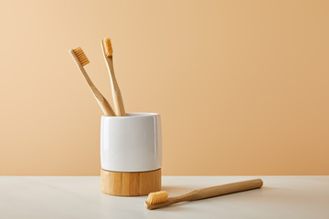 bamboo toothbrushes and holder on white table and beige background
