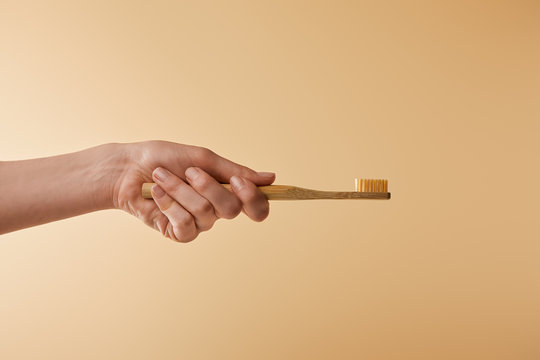 Cropped View Of Woman Holding Bamboo Brown Toothbrush On Beige Background