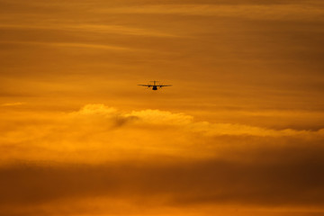 Fototapeta na wymiar Small plane in the middle of the red clouds at sunset