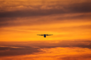 Naklejka na ściany i meble Small plane in the middle of the red clouds at sunset