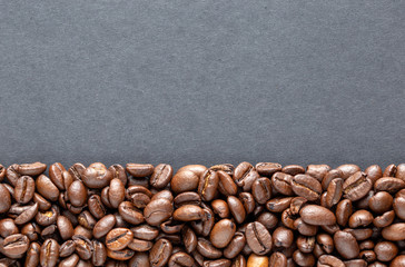 Coffee beans arranged at bottom of frame with text copy space on grey background