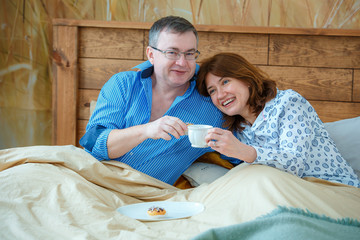 Photo session - friendly family. Morning tea. Husband brought his wife tea (coffee) to the bed.