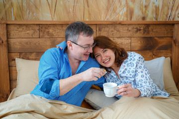 Photo session - friendly family. Morning tea. Husband brought his wife tea (coffee) to the bed.