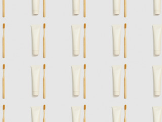bamboo toothbrushes and toothpaste in tubes on grey background, seamless background pattern