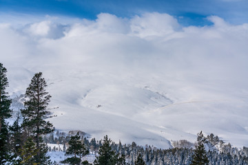 Magic winter mountain landscape: View over the mountain snow-capped peaks under the clouds Lago-Naki, The Main Caucasian Ridge, Russia