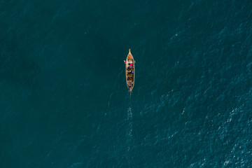 View from above, aerial view of a beautiful longtail boat sailing on a deep blue sea in Phuket, Thailand.