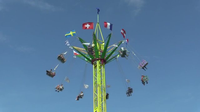 Roundabout chain, fun attraction, fairground with blue sky, carousel roundabout, swings amusement park, chain and iron steel structure with Czech, unrecognizable people enjoying ride, Europe