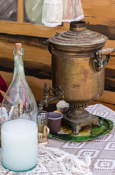 Samovar and moonshine bottle on a lace tablecloth. Rustic still life in traditional Russian style