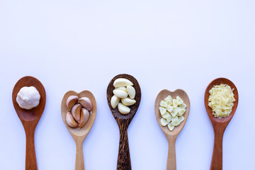 Garlic on wooden spoon on white