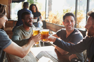 Group Of Male Friends Meeting In Sports Bar Making Toast Together