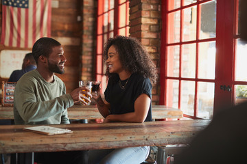 Young Couple Meeting In Sports Bar Making Toast Together