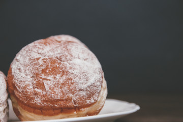 delicious donuts sprinkled with powdered sugar with filling on a dark background