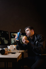 handsome guard eating burger and holding paper cup at workplace