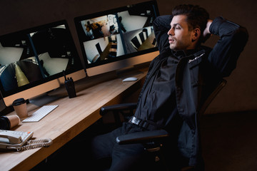  guard in uniform with crossed arms looking at computer monitor