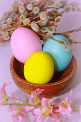 pink yellow blue eggs against a background of willow and flowers for the Easter holiday