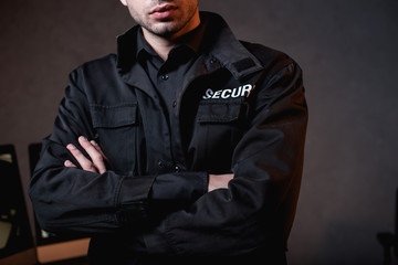 cropped view of guard in uniform with crossed arms at workplace