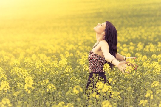 Free beautiful woman in happy summer love of youth wellbeing. Attractive young beauty girl enjoying the warm sunny sun in nature rapeseed field takes time feeling sustainability and contemplation
