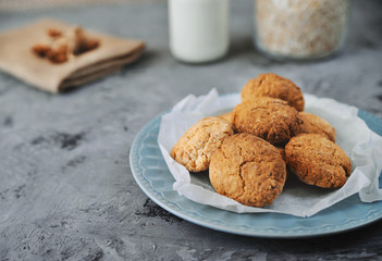 Oat cookies in blue plate with ingredients on wooden background.