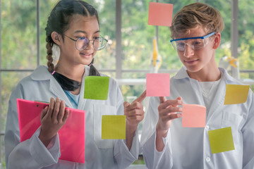 students pointing finger at note paper on glass board in laboratory