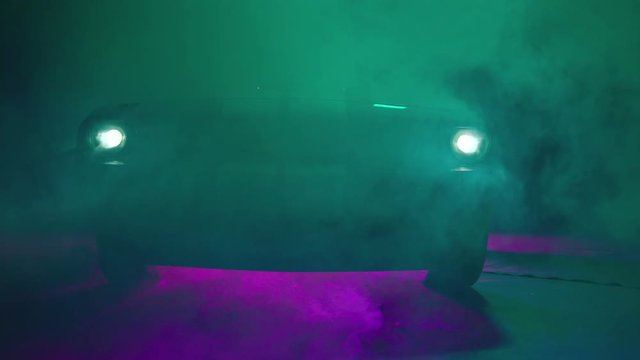 Silhouette of beautiful american muscle car on smoked dark background . Car lights on fog . 