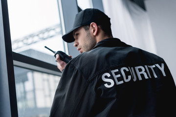 rear view of guard in uniform talking on walkie-talkie