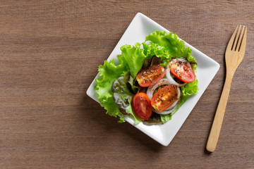 top view of vegetable salad in a ceramic dish on wooden table. homemade style healthy food concept.