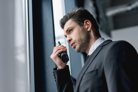 handsome bodyguard in suit using walkie-talkie - Powered by Adobe