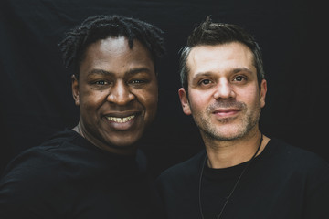 An interracial gay couple pose before the camera to have their pictures taken - black man and mixed...