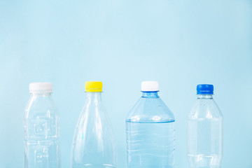 Plastic waste concept: discarded various water bottles in blue background, detailed view. Single use plastic bottles standing in row, image depicting excessive plastic use and pollution