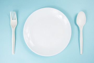 Dieting or anorexia concept: empty plate on a table. Top view of empty bowl on pale blue background, top view