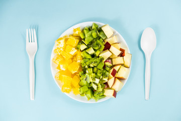 Plant based food diet concept. Top view of fresh fruit on a plate in pale blue background