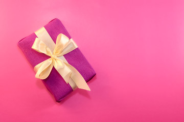 gift wrapped and decorated with a light bow on a pink background with copy space. Flat lay, top view. copy space
