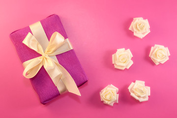 Gift box with rose flowers on pink background. flat lay